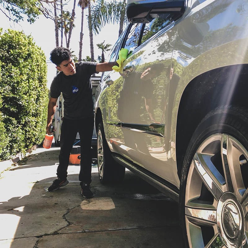 MobileWash washer does car cleaning, applying wax, for an auto detail to a white SUV, being the nearest car wash.