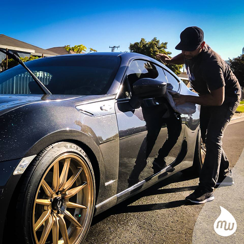 MobileWash washer doing a hand wash on a black sports car with gold rims for a mobile auto detailing from MobileWash.