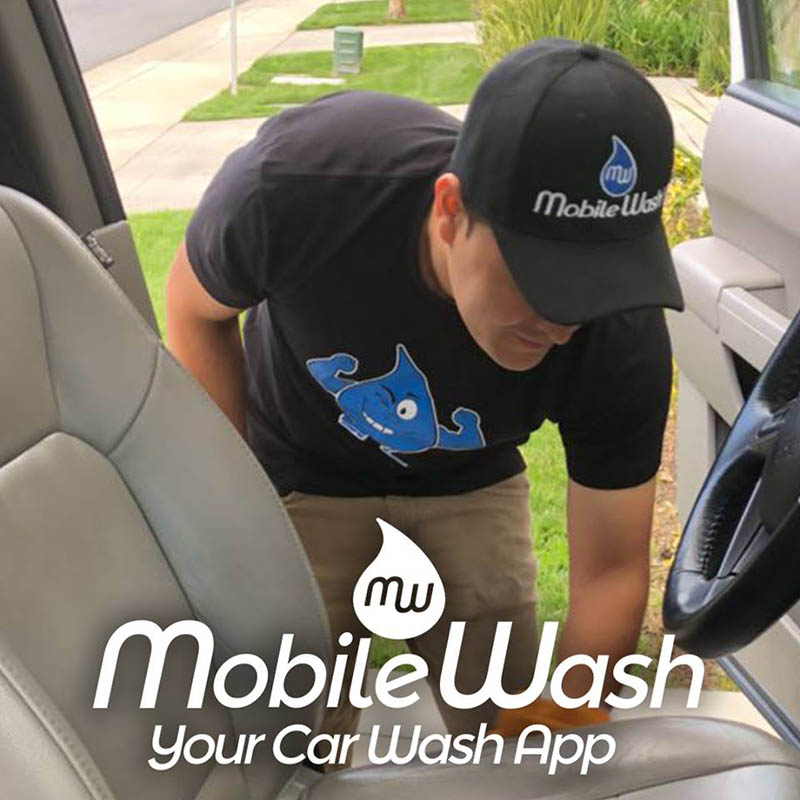 MobileWash washer does an interior clean, using a microfiber rag, on a customer's vehicle for a car cleaning.