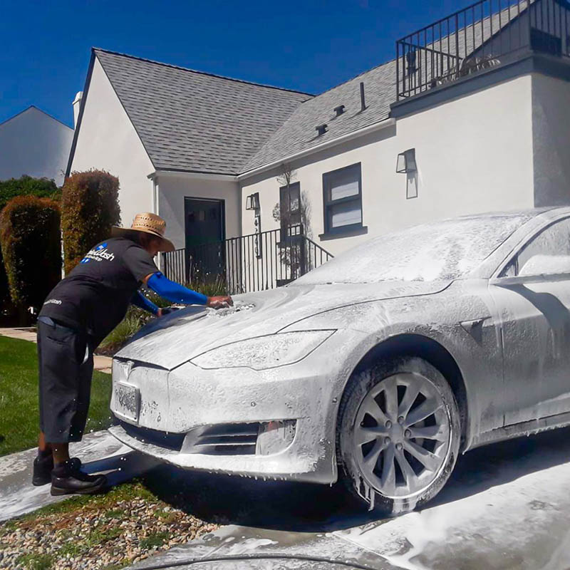 A MobileWash washer hand washing a Tesla car in Pasadena, for a proper car cleaning and mobile detailing service.