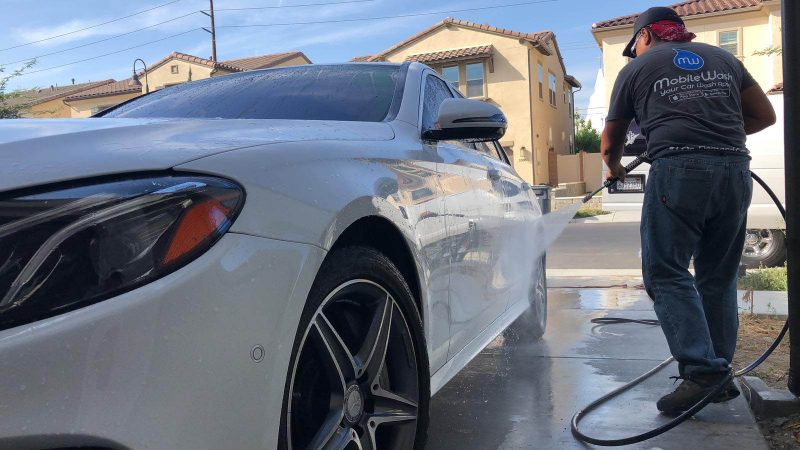 A MobileWash washer sprays down a white Mercedes Benz for auto detailing and quality mobile car detailing service.